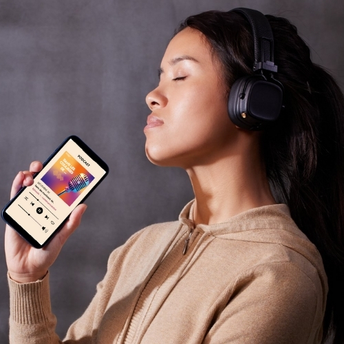 Femme portant un casque audio, tenant un smartphone affichant le podcast Dans les coulisses de ...